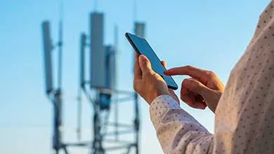 Person holding cell phone with cell towers in background