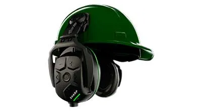 Green hard hat with integrated black electronic earmuffs on a white background. The left earmuff includes a button control panel and a glowing green LED indicator.