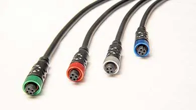 Close-up of four black cables with circular multi-pin connectors, each marked by a colored ring: green, red, gray, and blue.
