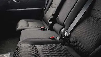 Close-up of dark gray cloth car back seats, showing a textured cushion pattern and visible seat belts.